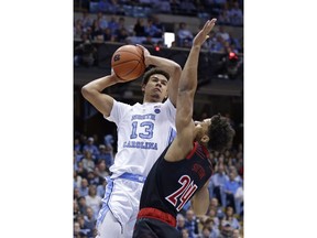 North Carolina's Cameron Johnson (13) drives to the basket as Louisville's Dwayne Sutton (24) defends during the first half of an NCAA college basketball game in Chapel Hill, N.C., Saturday, Jan. 12, 2019.