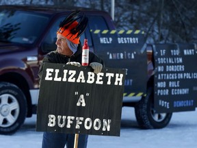 A protester, who declined to give his name but did say he was a naturalized U.S. citizen from Canada and a refugee from socialism, stands at the entrance to Manchester Community College in Manchester, N.H., Saturday, Jan. 12, 2019, before Sen. Elizabeth Warren, D-Mass., is due to speak at a rally there.