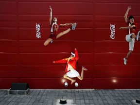 FILE - In this Aug. 20, 2008 file photo, a young girl mimics the pose of a Chinese Olympic athletes depicted in Coca-Cola advertising, at the Olympic green in Beijing.   The International Life Science Institute, a group funded by the food industry, undermined China's efforts to keep obesity rates in check by overemphasizing the importance of physical activity rather than dietary restrictions, according to a new paper. The group sponsored obesity conferences on exercise science with speakers including Coke-funded researchers and a Coke executive. ILSI says it does not profess to have been perfect, but that it has adopted stricter guidelines.