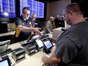 FILE - In this Dec. 13, 2018, file photo, Ryan Martin, right, looks over his wager at Rivers Casino, as the new, temporary sports betting area opened in Pittsburgh. Pending Pennsylvania Gaming Control Board approval, regular operations are scheduled to begin Saturday, Dec. 15. Marton made several wagers, including placing a $100 bet on the Pittsburgh Steelers to win the Super Bowl. Anyone willing to wager that the high-scoring Patriots or Rams will get shut out in the Super Bowl can count on a big payday if that unlikely scenario occurs. Prop bets aren't a big moneymaker for sports books during the season, but they pick up popularity as the nation is intensely focused on a single game.