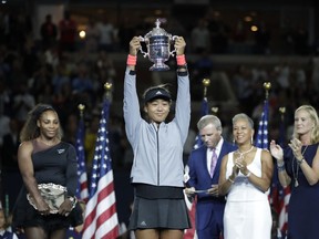 FILE - In this Sept. 8, 2018, file photo, Naomi Osaka, of Japan, holds the trophy after defeating Serena Williams in the women's final of the U.S. Open tennis tournament, in New York. Caroline Wozniacki will be defending a Slam title for the first time after winning in Melbourne a year ago, while Naomi Osaka will enter a major tournament with the label "major champion" for the first time after taking home the trophy at the U.S. Open in September.