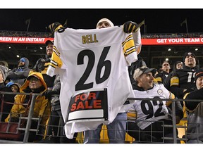 FILE - In this Nov. 8, 2018, file photo, a Pittsburgh Steelers fan holds a Le'Veon Bell jersey during the second half of an NFL football game between the Steelers and the Carolina Panthers in Pittsburgh. The steady exodus of mid-level veterans from the NFL is one element of a long-standing tension between players and the league over the structuring of contracts. The contract holdouts by Bell and Earl Thomas this season put the issue into vivid focus.
