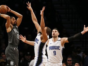 Brooklyn Nets guard Spencer Dinwiddie (8) looks to pass around Orlando Magic guard Isaiah Briscoe and Orlando Magic center Nikola Vucevic (9) during the first half of an NBA basketball game Wednesday, Jan. 23, 2019, in New York.