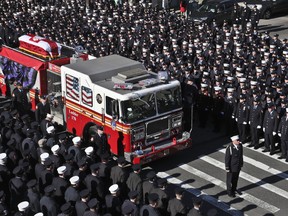 Fallen firefighter Steven Pollard's casket is driven on his fire house truck through a roadway lined with thousands of firefighters, Friday Jan. 11, 2019, in New York. The 30-year-old was assigned to Ladder 170 of the Fire Department of New York when he was fatally injured last Sunday on Brooklyn's Belt Parkway.