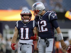 FILE - In this Aug. 9, 2018, file photo, New England Patriots wide receiver Julian Edelman (11) talks with quarterback Tom Brady (12) before a preseason NFL football game against the Washington Redskins in Foxborough, Mass. There's just two receivers in NFL postseason history with over 100 catches – Jerry Rice with 151 and Edelman with 105. That link has only been strengthened off the field in the past year as Brady and Edelman prepare to play in their fourth Super Bowl together.