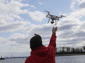 FILE - In this April 29, 2018, file photo, a drone operator helps to retrieve a drone after photographing over Hart Island in New York. Drone sightings reported by airline pilots over New Jersey renew questions about how to accommodate the popular devices into the nation's airspace. The ability of drones to interfere with aviation is likely to get worse as the number of machines multiplies. Many store-bought drones come with technology to prevent owners from flying them near airports, but there are hacks, and home-built machines don't necessarily include those protections.