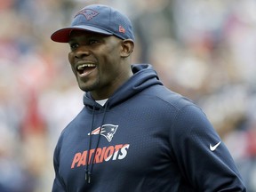 FILE - In this Sept. 9, 2018, file photo, New England Patriots linebackers coach Brian Flores watches his team warm up before an NFL football game against the Houston Texans in Foxborough, Mass. Flores' team is headed for the Super Bowl, and the Miami Dolphins must wait another two weeks before they can seal a deal with the New England Patriots' defensive play-caller to become their coach. The Dolphins decided nearly two weeks ago to offer the job to Flores, who has been a Patriots assistant for 11 seasons.