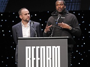 Philadelphia 76ers co-owner and Fanatics executive Michael Rubin, left, listens as recordng artist Meek Mill speaks at the launch of a partnership of sports, business and recording artists who hope to transform the American criminal justice system, Wednesday, Jan. 23, 2019, in New York.