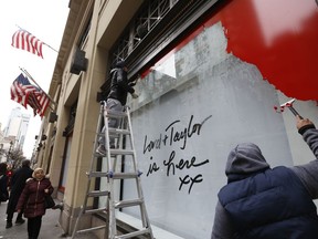 Workers scrape a sign off a display window outside Lord & Taylor's flagship Fifth Avenue store after it closed for good mid-afternoon, Wednesday, Jan. 2, 2019, in New York. The venerable 104 year-old department stored known for its animated Christmas windows closed after a blowout sale that left whole floors empty.