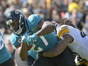 FILE - In this Nov. 18, 2018, file photo, Jacksonville Jaguars running back Leonard Fournette, left, runs for yardage as he is stopped by Pittsburgh Steelers outside linebacker Bud Dupree, right, during the first half of an NFL football game in Jacksonville, Fla. A person familiar with the situation says the Jacksonville Jaguars have notified running back Leonard Fournette that his suspension late last month voided the remaining guarantees in his four-year rookie contract. The person spoke to The Associated Press on the condition of anonymity Sunday night, Dec. 30, 2018 .