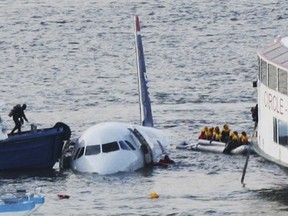 FILE - In this Jan. 15, 2009 file photo, a diver, left, aboard an NYPD vessel prepares to rescue passengers that escaped from the Airbus 320 US Airways aircraft made an emergency landing in the Hudson River in New York in what came to be known as the "Miracle on the Hudson" because everyone survived. It's been 10 years since US Airways flight 1549 landed on the Hudson River after colliding with a flock of geese just after takeoff.