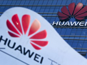 FILE - This Tuesday, Dec. 18, 2018, file photo, shows company signage on display near the Huawei office building at its research and development center in Dongguan, in south China's Guangdong province. A federal indictment accuses Huawei of stealing trade secrets from T-Mobile, in the form of a robot designed to automatically test phones for problems.