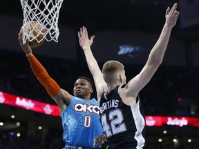 Oklahoma City Thunder guard Russell Westbrook (0) drives to the basket past San Antonio Spurs forward Davis Bertans (42) in the first half of an NBA basketball game in Oklahoma City, Saturday, Jan. 12, 2019.