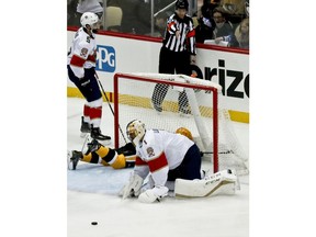 The puck kicks out in front of Florida Panthers goaltender Roberto Luongo (1) as Pittsburgh Penguins' Bryan Rust slides into the goal after scoring during the first period of an NHL hockey game Tuesday, Jan. 8, 2019, in Pittsburgh.