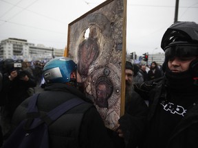 A demonstrator kisses a representation of the Virgin Mary and child during clashes following a rally in Athens, Sunday, Jan. 20, 2019. Greece's Parliament is to vote this coming week on whether to ratify the agreement that will rename its northern neighbor North Macedonia. Macedonia has already ratified the deal, which, polls show, is opposed by a majority of Greeks.