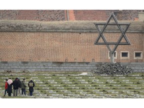 Visitors walk through the cemetery of the former Nazi concentration camp in Terezin, Czech Republic, Thursday, Jan. 24, 2019. A unique collection of some 4,500 drawings by children who were interned at the Theresienstadt concentration camp during the Holocaust now displayed in the Pinkas Synagogue, still attracts attention even after 75 years since their creation. The drawings depict the everyday life as well hopes and dreams of returning home.