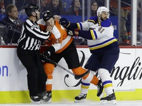 Philadelphia Flyers' James van Riemsdyk, center, is shoved into an official by St. Louis Blues' Robert Bortuzzo, right, during the first period of an NHL hockey game, Monday, Jan. 7, 2019, in Philadelphia.