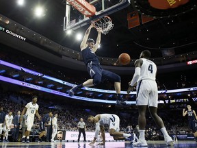 Xavier's Zach Hankins (35) hangs from the rim after a dunk during the first half of the team's NCAA college basketball game against Villanova, Friday, Jan. 18, 2019, in Philadelphia.