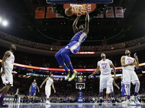 Philadelphia 76ers' Joel Embiid, center, hangs on the rim after a dunk during the first half of an NBA basketball game against the Minnesota Timberwolves, Tuesday, Jan. 15, 2019, in Philadelphia.