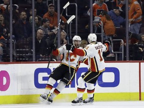 Calgary Flames' TJ Brodie, left, celebrates with Mikael Backlund after Brodie scored the game-winning goal in overtime of an NHL hockey game against the Philadelphia Flyers, Saturday, Jan. 5, 2019, in Philadelphia. Calgary won 3-2.