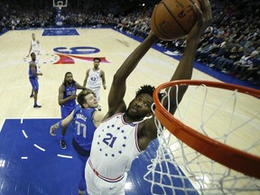 Philadelphia 76ers' Joel Embiid (21) goes up for a dunk past Dallas Mavericks' Luka Doncic (77) during the first half of an NBA basketball game, Saturday, Jan. 5, 2019, in Philadelphia.