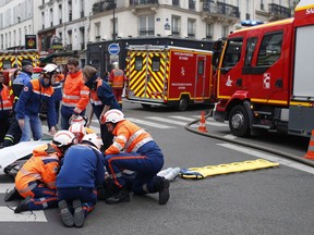 Firefighters tends to a wounded person near the site of a gas leak explosion in Paris, France, Saturday, Jan. 12, 2019. A powerful explosion and fire apparently caused by a gas leak at a Paris bakery Saturday injured several people, blasted out windows and overturned cars, police said.