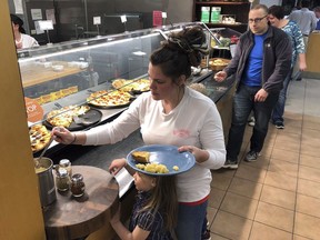 U.S. Coast Guard spouse Rachel Malcom, left, gathers food for herself and her daughter, Tuesday, Jan. 15, 2019, at Roger Williams University in Bristol, R.I. The college offered a free dinner for active-duty Coast Guard members and their families in Rhode Island and southeastern Massachusetts who are working without pay during the partial federal shutdown. The Coast Guard is affected because it's part of the Department of Homeland Security. Other military services receive funding through the Defense Department.