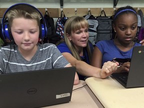 In this Sept. 20, 2018 photo, fifth grade teacher Heather Dalton, center, works with students Julian Ryno, left, and Ma'Kenley Burns, doing math problems on the DreamBox system at Charles Barnum Elementary School in Groton, Conn. A wide array of apps, websites and software used in schools borrow elements from video games to help teachers connect with students living technology-infused lives.