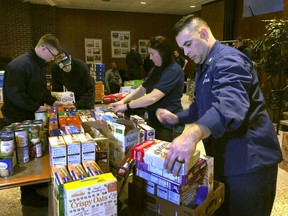 In this Thursday, Jan. 17, 2019 photo, U.S. Coast Guard Culinary Specialist Jerry Wright, right, and Petty Officer 2nd Class Lauren Laughlin, second from right, stack boxes of donated cereal at a pop-up food pantry created at the Coast Guard Academy in New London, Conn. The pantry was created by local Coast Guard-related advocacy groups to help hundreds of civilian and non-civilian Coast Guard employees to help makes ends meet during the partial federal government shutdown.