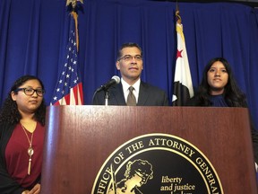 FILE - In this Monday, Sept. 11, 2017, file photo, California Attorney General Xavier Becerra is flanked by Rosa Barrientos, of East Los Angeles, left, and Eva Jimenez, of Visalia, right, as he announces a lawsuit challenging the Trump administration's decision to end a program that shields young immigrants from deportation, in Sacramento, Calif. Becerra and members of his staff in recent interviews discussed the DACA lawsuit as part of a broader glimpse into the office's decision-making and structure to fight Trump administration policies.