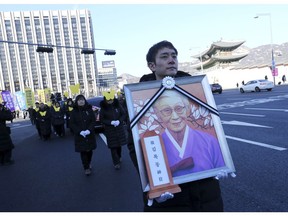 A mourner with a portrait of the deceased Kim Bok-dong, one of the former South Korean sex slaves who were forced to serve for the Japanese military in World War II, marches toward the Japanese Embassy during her funeral ceremony in Seoul, South Korea, Friday, Feb. 1, 2019. Hundreds of mourners gathered Friday near the Japanese Embassy in Seoul for the funeral of the South Korean woman forced as a girl into a brothel and sexually enslaved by the Japanese military in WWII.