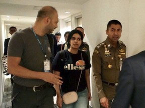 FILE - In this Jan. 7, 2019, file photo released by the Immigration Police, Chief of Immigration Police Maj. Gen. Surachate Hakparn, right, walks with Saudi woman Rahaf Mohammed Alqunun before leaving the Suvarnabhumi Airport in Bangkok, Thailand. Australia says it is considering granting the Saudi who fled from her family refugee resettlement based on referral by the U.N. (Immigration police via AP, File)