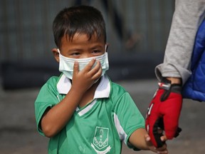 A young boy wears a protective mask for the high levels of air pollution as he's picked up from school in Bangkok, Thailand, Wednesday, Jan. 30, 2019. Over 400 schools in Bangkok have been ordered shut Wednesday as the Thai capital sees continuously high levels of air pollution and dust particles.