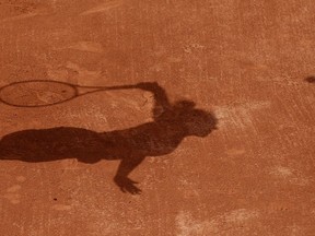 FILE - In this Tuesday, May 30, 2017 file photo a tennis player casts a shadow on the clay as they serve during a tennis match at the French Open tennis tournament at the Roland Garros stadium in Paris. Four people are in French custody on suspicion of fixing matches for an Armenian based in Belgium believed behind an illegal gambling syndicate suspected of fixing hundreds of matches.