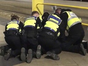UGC issued by PA shows Police restraining a man after he stabbed three people at Victoria Station in Manchester, England, late Monday Dec. 31, 2018. Two commuters - a man and woman in their 50s - were taken to hospital with knife injuries and a British Transport Police (BTP) officer was stabbed in the shoulder. Police said a man was arrested on suspicion of attempted murder and remains in custody.