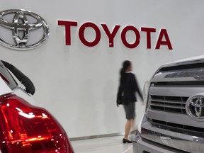 FILE - In this May 10, 2017, file photo, a visitor walks past the logo of Toyota Motor Corp. at a Toyota showroom in Tokyo. Toyota Motor Corp. said Wednesday, Jan. 30, 2019, it sold 10.59 million vehicles globally last year, fewer than the 10.83 million delivered by German rival Volkswagen AG.