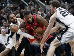 Toronto Raptors center Greg Monroe, center, is pressured by San Antonio Spurs guard Patty Mills, left, and center Jakob Poeltl (25) during the first half of an NBA basketball game, Thursday, Jan. 3, 2019, in San Antonio.
