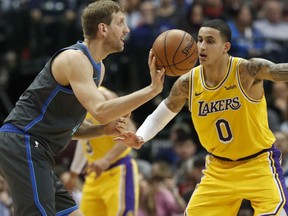 Dallas Mavericks forward Dirk Nowitzki, left, of Germany, passes off against Los Angeles Lakers forward Kyle Kuzma (0) during the first quarter of an NBA basketball game in Dallas, Monday, Jan. 7, 2019.