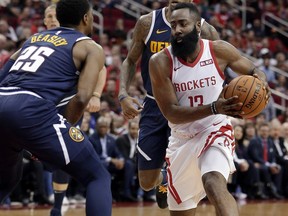 Houston Rockets guard James Harden (13) drives to the basket between Denver Nuggets guard Malik Beasley (25) and forward Torrey Craig, back, during the second half of an NBA basketball game Monday, Jan. 7, 2019, in Houston.