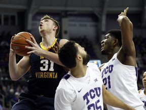 West Virginia forward Logan Routt (31) leaps to the basket for a shot as TCU guard Alex Robinson (25) and center Kevin Samuel (21) defend in the first half of an NCAA college basketball game, Tuesday, Jan. 15, 2019, in Fort Worth, Texas.