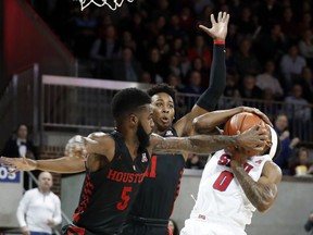 SMU guard Jahmal McMurray (0) is fouled by Houston guard Corey Davis Jr. (5) going up for a shot as Houston's Nate Hinton (11) helps defend beneath the basket in the first half of an NCAA college basketball game, Wednesday, Jan. 16, 2019, in Dallas.