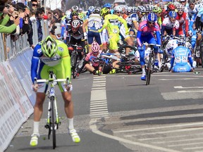 Pro cyclist Taylor Phinney (pink jersey) sits on the ground 100 metres from the finish line on May 7, 2012 after falling during the Giro d'Italia. Phinney says the combination of crushed-up painkillers and caffeine pills in athletes’ bottles leads to late-race crashes.