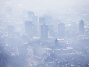 FILE - In this Jan. 18, 2017, file photo, smog covers Salt Lake City as an inversion lingers. When it comes to their views on climate change, Americans are looking at natural disasters and their local weather, according to a new poll.