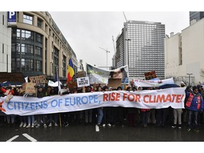 Protestors hold a banner as they march during a Rise for the Climate demonstration in Brussels, Sunday, Jan. 27, 2019.