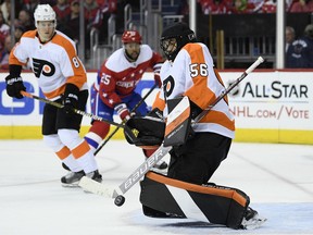 Philadelphia Flyers goaltender Mike McKenna (56) stops the puck during the second period of an NHL hockey game as Washington Capitals right wing Devante Smith-Pelly (25) watches, Tuesday, Jan. 8, 2019, in Washington. Also seen is Flyers defenseman Robert Hagg (8).