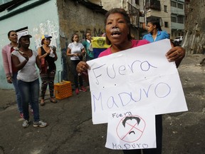 A woman with toothpaste under her nose to help with the effects of tear gas fired by security forces holds a sign that reads in Spanish "Get out Maduro," referring to Venezuelan President Nicolas Maduro, in the Cotiza neighborhood of Caracas, Venezuela, Monday, Jan. 21, 2019. Security forces have fired tear gas against protesters in a poor neighborhood near the presidential palace after an apparent uprising by a national guard unit.