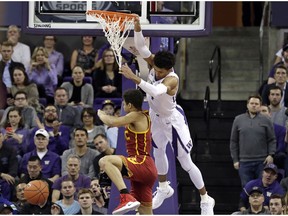 Washington's Matisse Thybulle swings from the basket after dunking over Southern California's Derryck Thornton during the first half of an NCAA college basketball game Wednesday, Jan. 30, 2019, in Seattle.