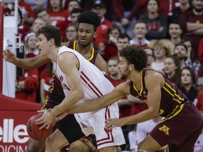 Wisconsin's Ethan Happ (22) drives against Minnesota's Eric Curry, behind, and Gabe Kalscheur, right, during the first half of an NCAA college basketball game Thursday, Jan. 3, 2019, in Madison, Wis.