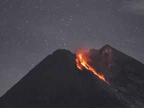 In this Tuesday, Jan, 29, 2019, photo. Mount Merapi spews volcanic material as it erupts as seen from Cangkringan, Yogyakarta, Indonesia. Indonesia's most volatile volcano unleashed a 1,400 meters (4,600 feet) dark red volcanic material 1,400 meters (1,500 yards) down the slopes.