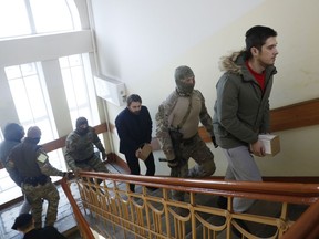 CORRECTS PHOTOGRAPHER NAME  Ukrainian sailors are escorted by a Russian intelligence agency FSB officer to a court room in Moscow, Russia, Tuesday, Jan. 15, 2019. 24 Ukrainian seamen were captured and taken into Russia custody in November, after a Russian coast guard vessel fired on and seized three Ukrainian naval ships off the Russia-occupied Crimean peninsula.